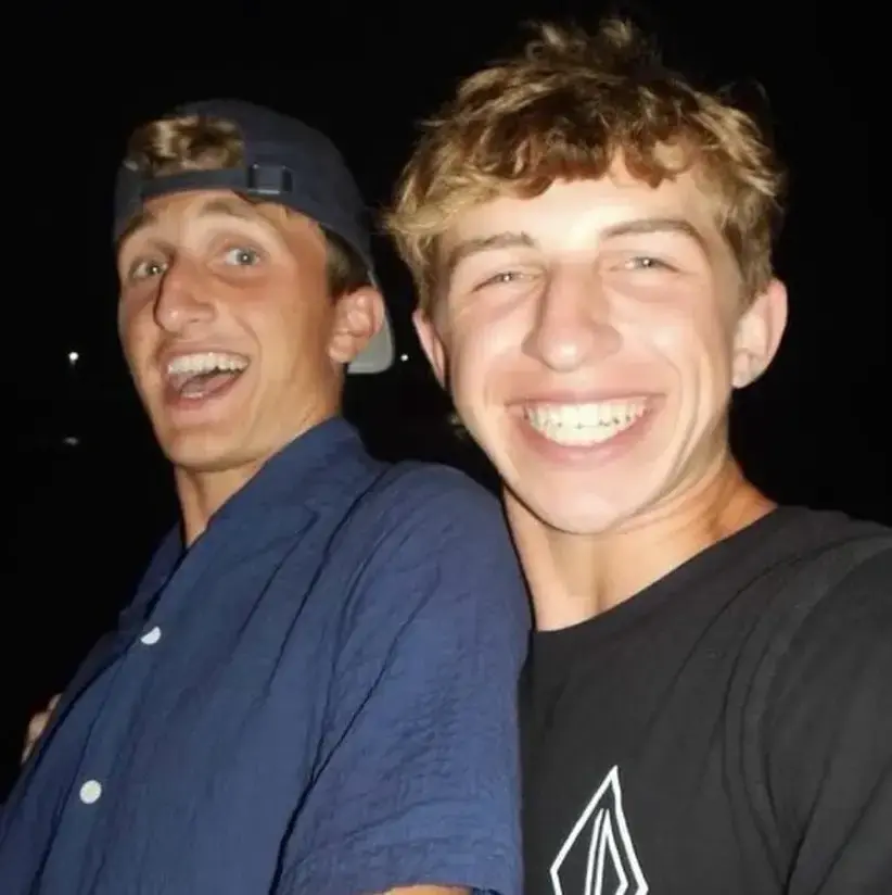 Mitchell and a friend smiling broadly in a nighttime setting, conveying excitement.